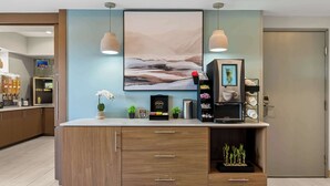 A modern kitchen with wooden cabinets, a countertop, and a large painting above. - Best Western Executive Inn (Seagoville)