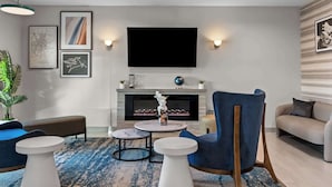 A modern living room with a fireplace, a flat-screen TV, and a blue armchair. - Best Western Executive Inn (Seagoville)