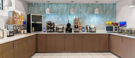 Cozinha moderna com ilha central, eletrodomésticos embutidos e painel de azulejos.