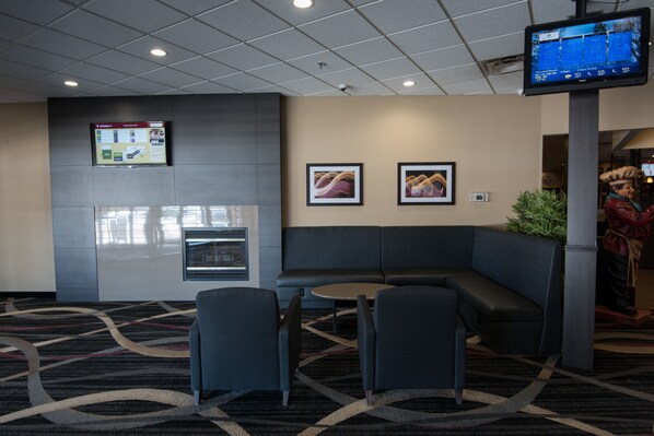 A hotel lobby with a seating area, a digital screen, and a fireplace. - Victoria Inn Hotel & Convention Centre Brandon (Brandon)