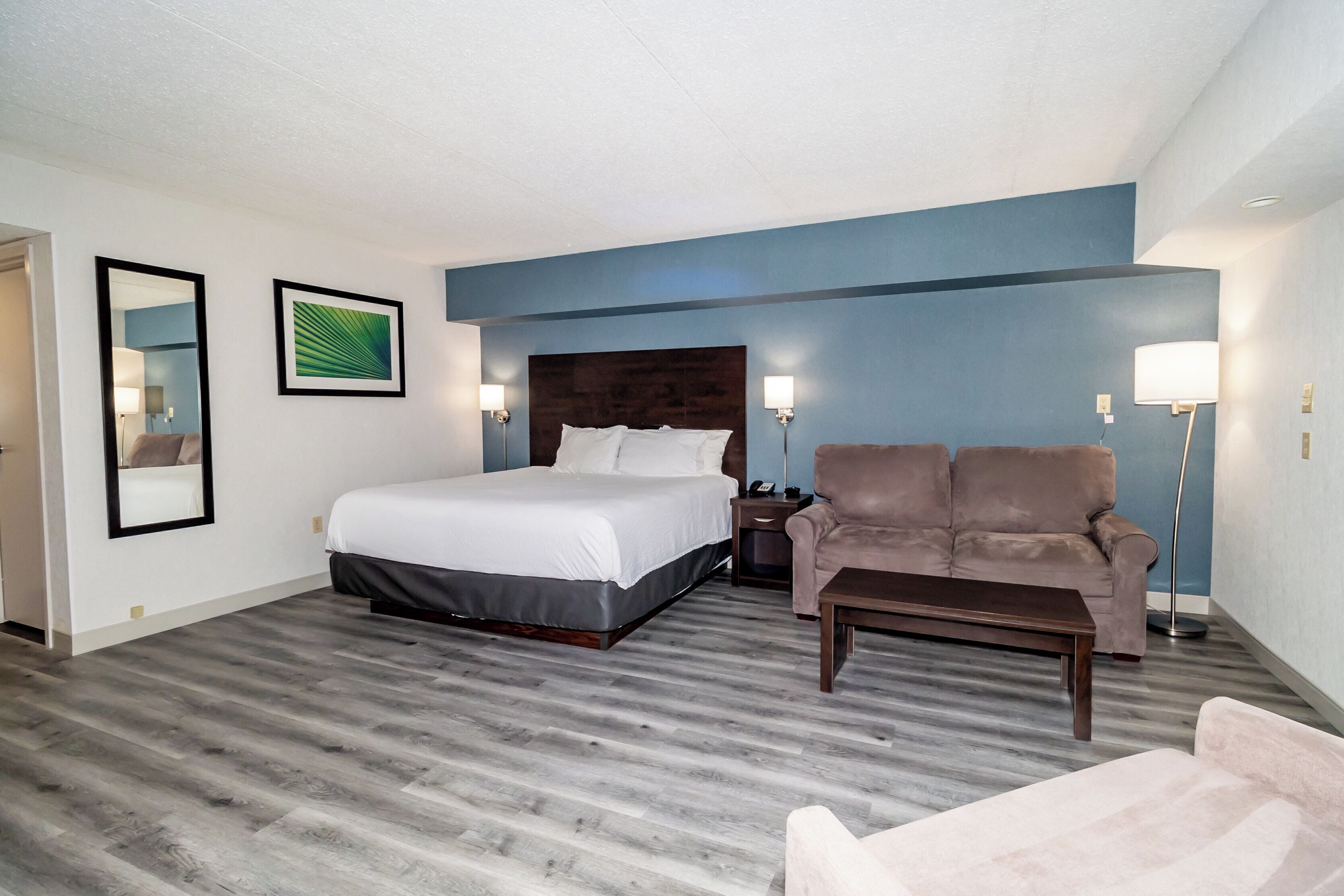 A hotel room with a bed, two armchairs, a coffee table, and a nightstand.