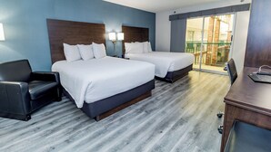 A hotel room with two beds, a desk, a chair, and a balcony with a view. - Victoria Inn Hotel & Convention Centre Brandon (Brandon)