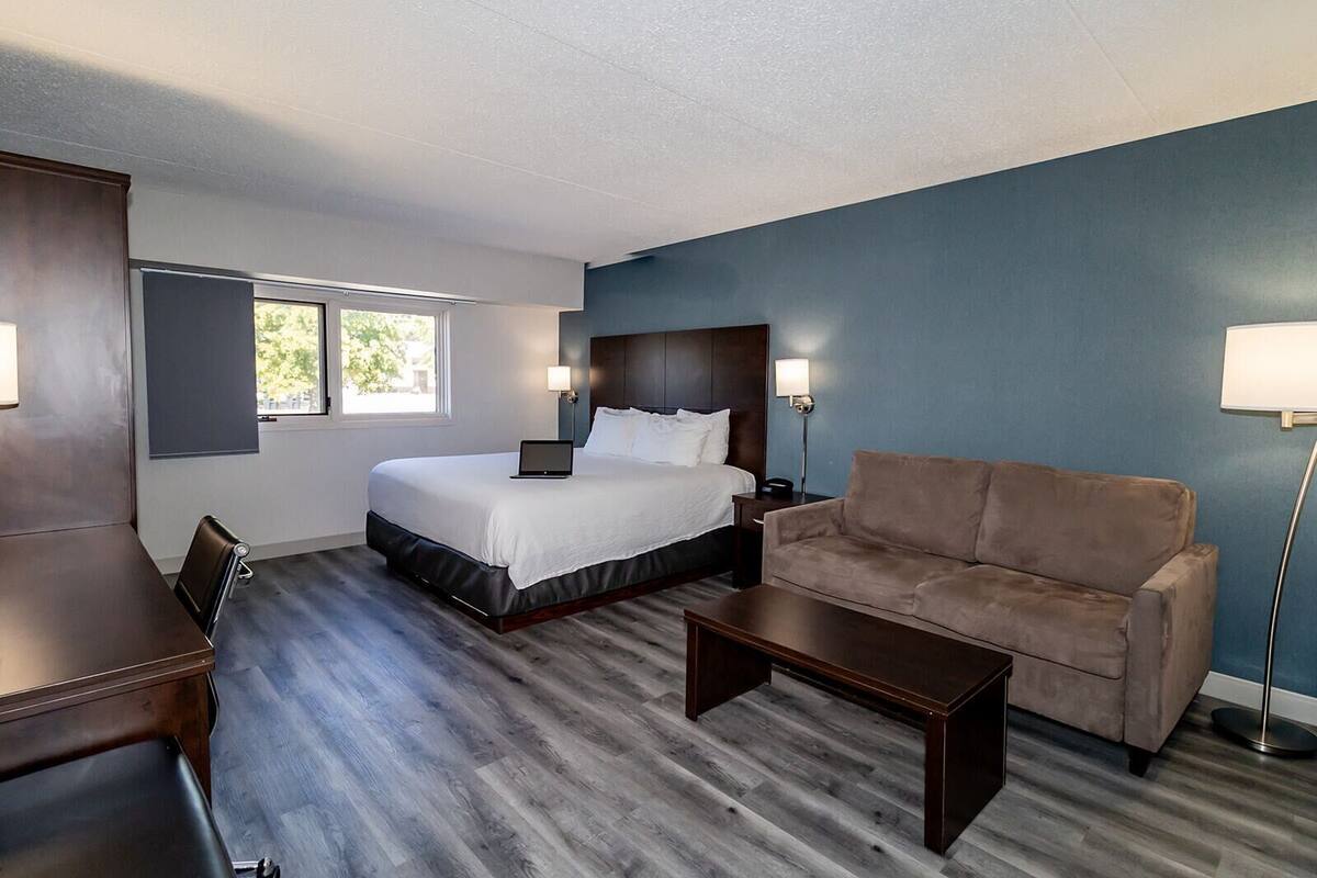 Une chambre d’hôtel avec un lit, un canapé, un bureau et une lampe.