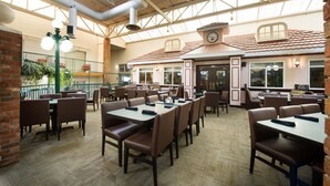 A spacious indoor dining area with high ceilings and natural light. Tables and chairs are arranged for dining. - Victoria Inn Hotel & Convention Centre Brandon (Brandon)