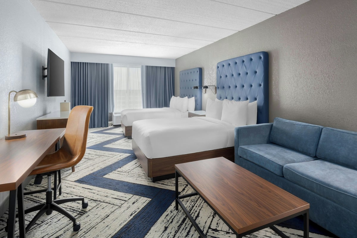 Ein Hotelzimmer mit einem großen Bett, einer Couch, einem Schreibtisch und einem Fernseher.