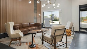 A modern lobby with a brown leather sofa, beige armchairs, and a round coffee table.