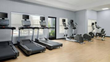 Academia com esteiras, elípticos e máquinas de musculação.
