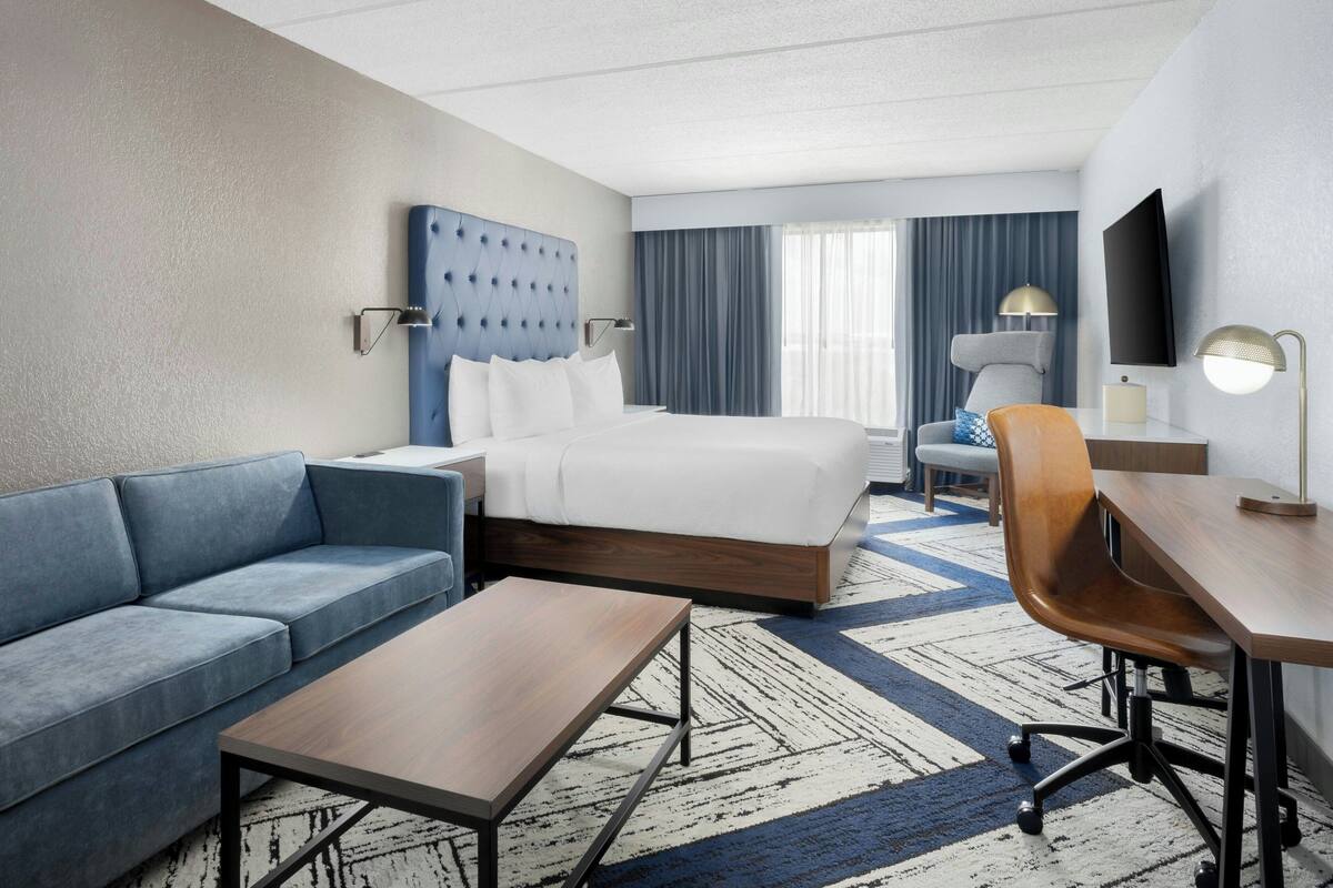 Ein Hotelzimmer mit Bett, Sofa, Schreibtisch und Fernseher.