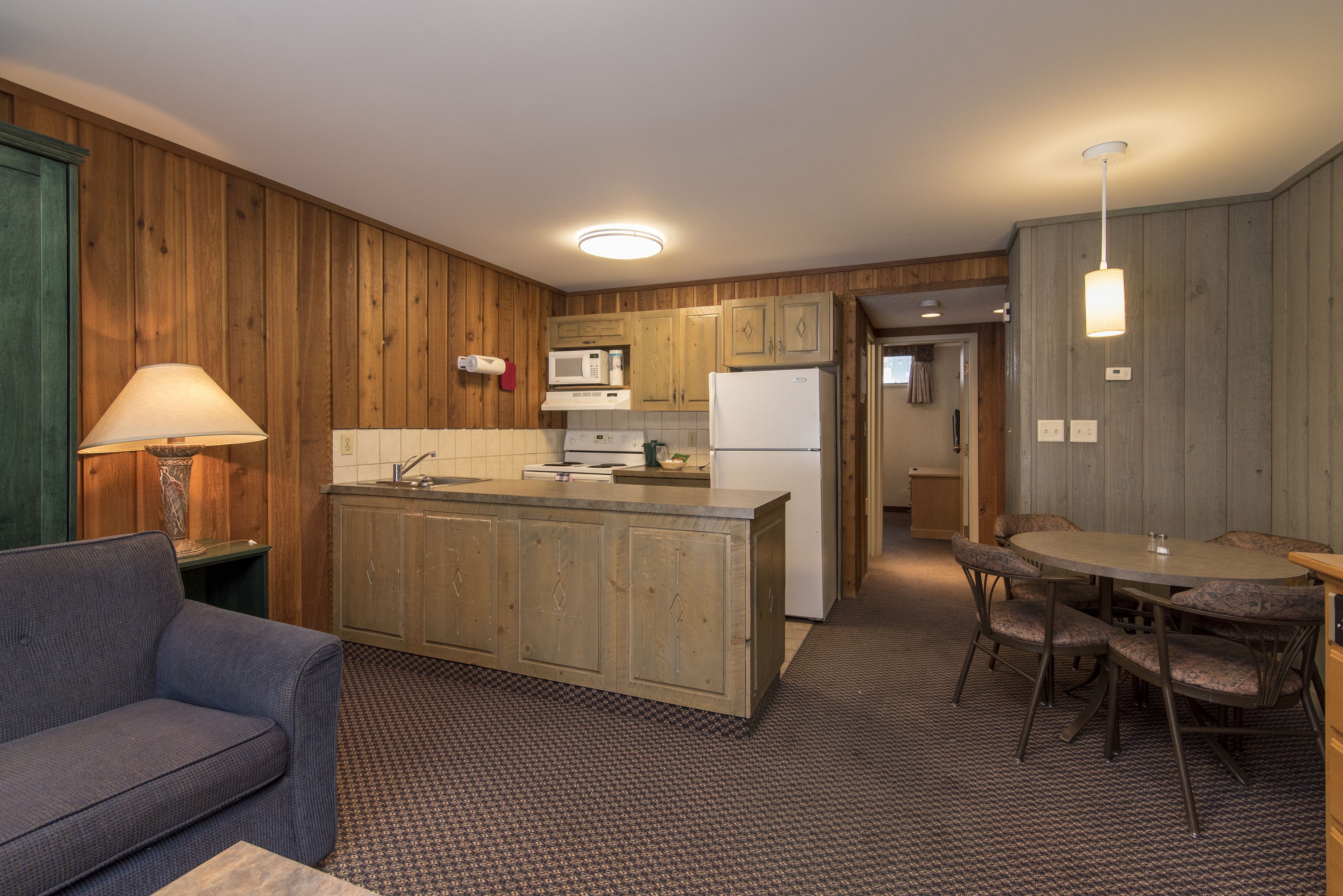 A compact kitchen with wooden cabinets, a central island, and a dining area with a table and chairs.