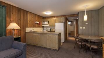 A compact kitchen with wooden cabinets, a central island, and a dining area with a table and chairs.