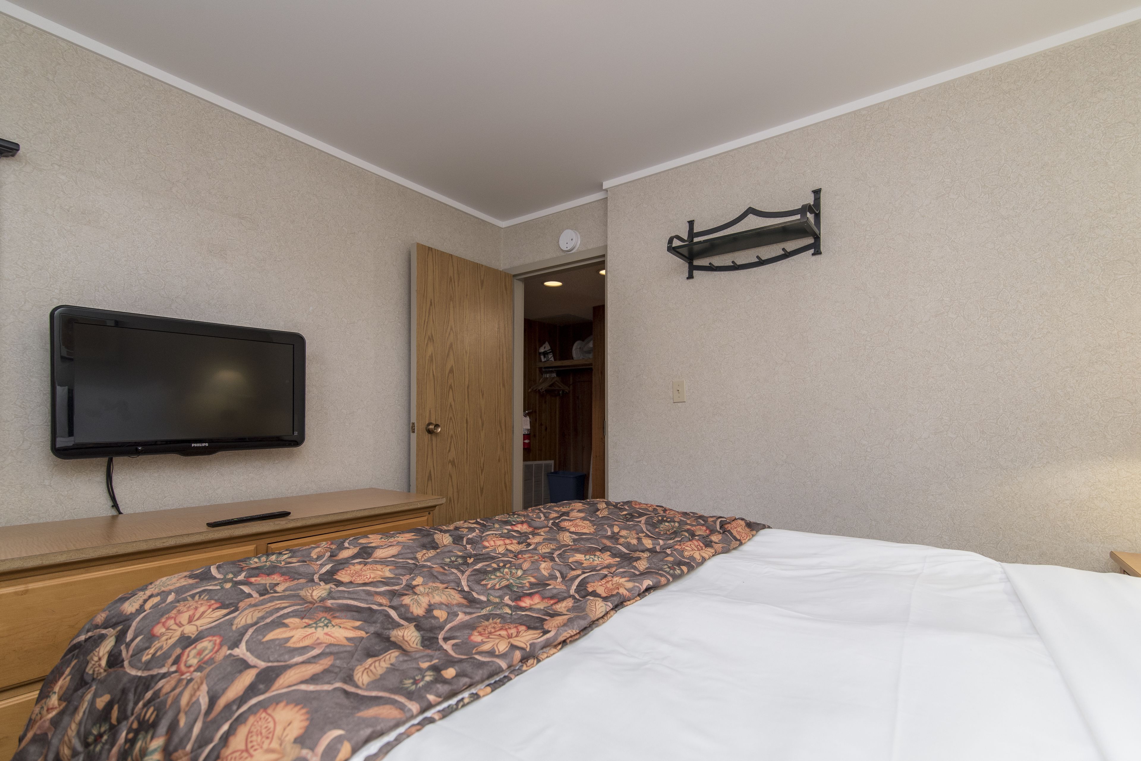 A bedroom with a bed, a television on a dresser, and a closet.