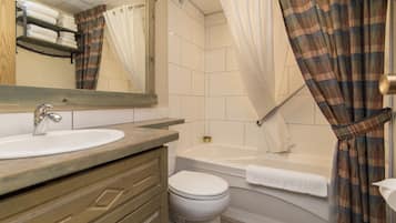 A bathroom with a sink, mirror, toilet, and bathtub.