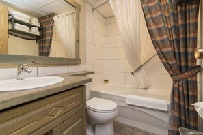 A bathroom with a sink, mirror, toilet, and bathtub. - Douglas Fir Resort and Chalets (Banff)