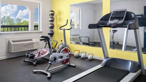 A gym with a stationary bike, elliptical, treadmill, and kettlebells.