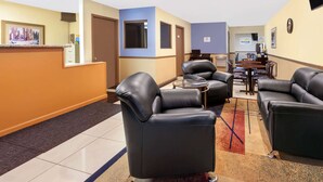 A hotel lobby with a reception desk, leather seating, a small dining area, and a Daybreak sign.