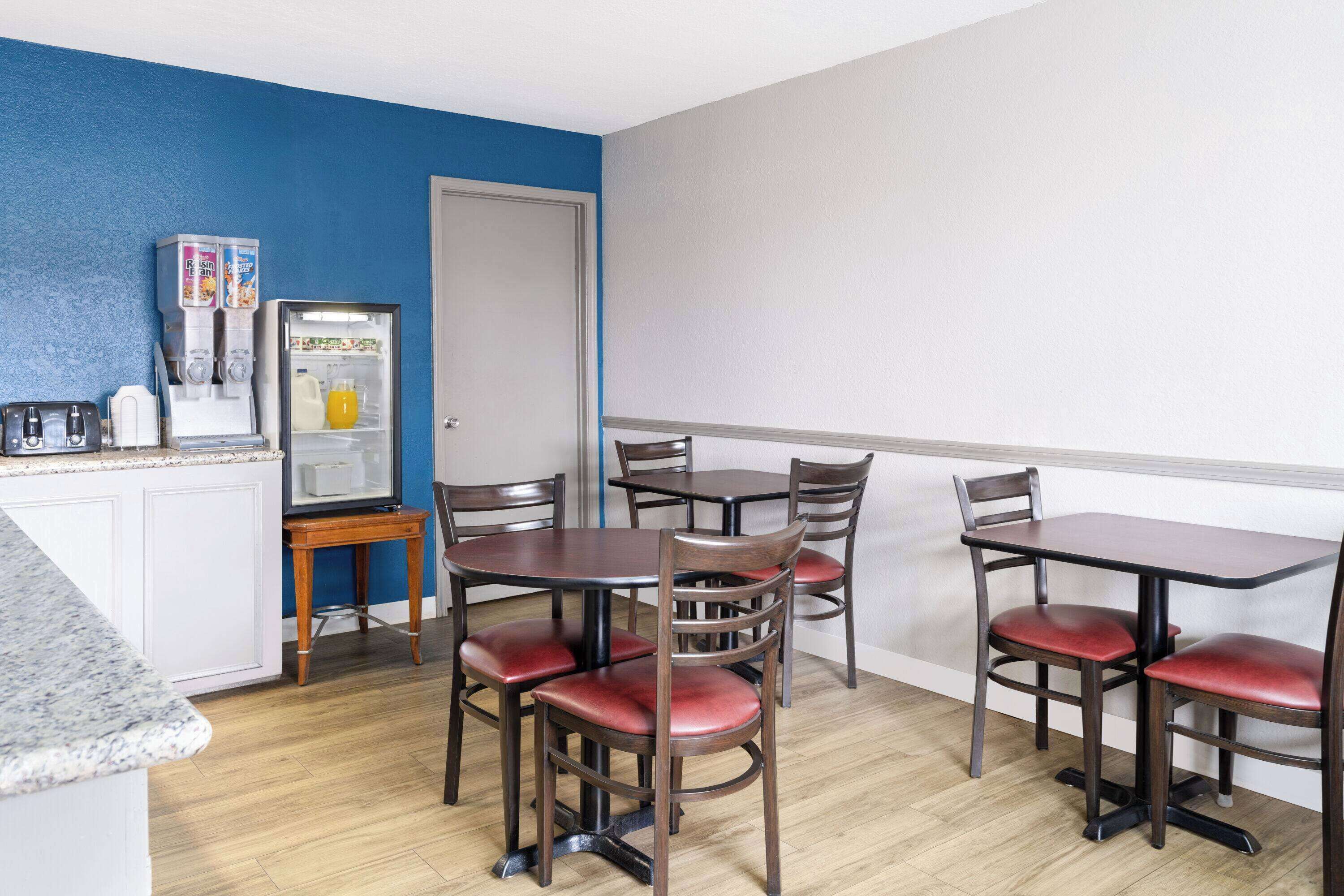A dining area with a refrigerator, a juice dispenser, and a microwave.