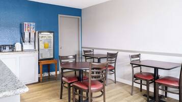 A dining area with a refrigerator, a juice dispenser, and a microwave.