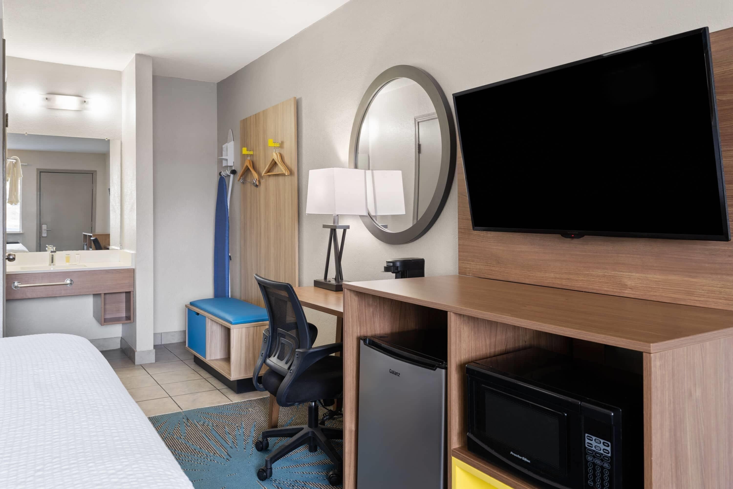 Hotelkamer met een bed, bureau met computer, televisie, magnetron en kleine koelkast.