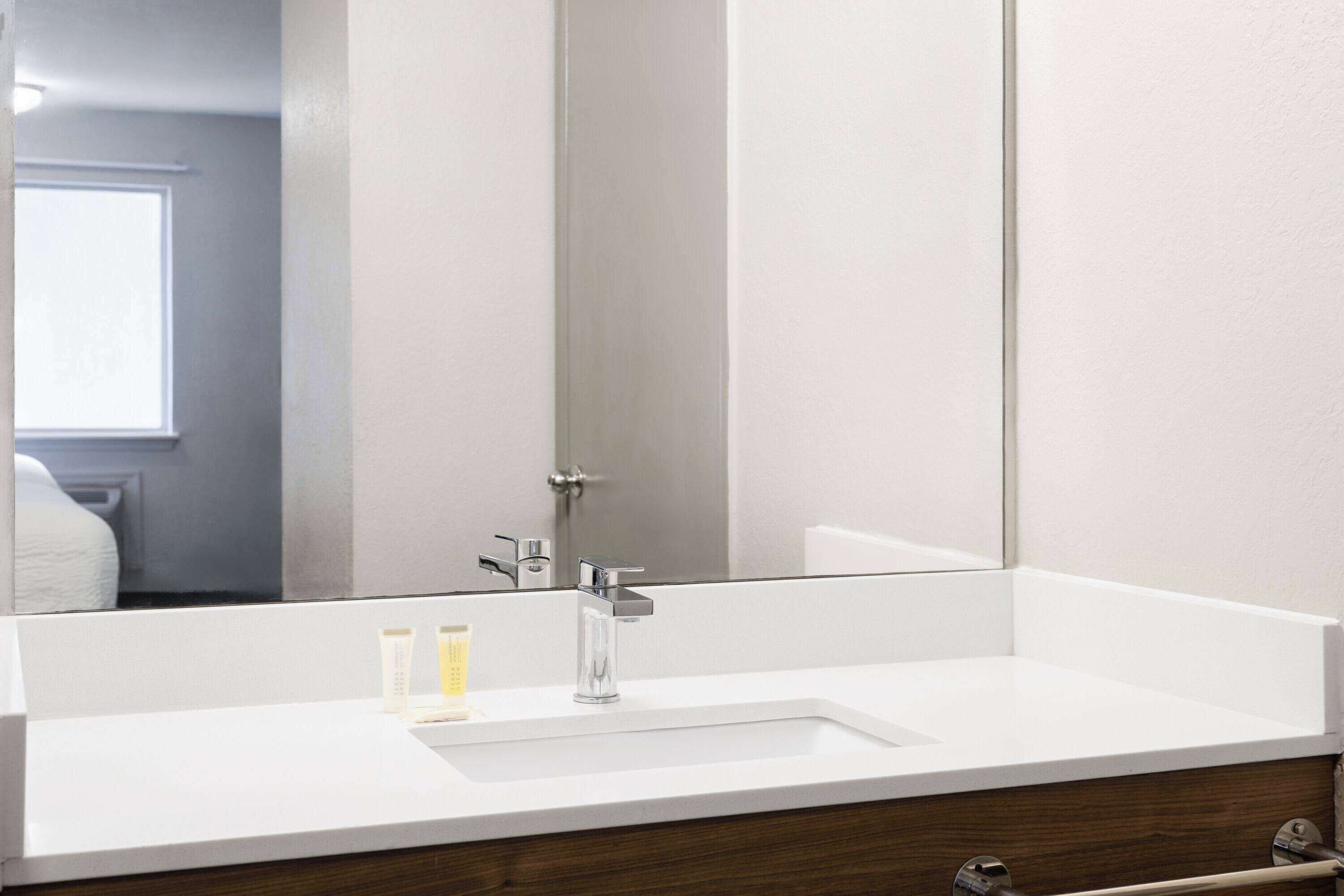 A bathroom with a white sink, a mirror, and a wooden vanity.
