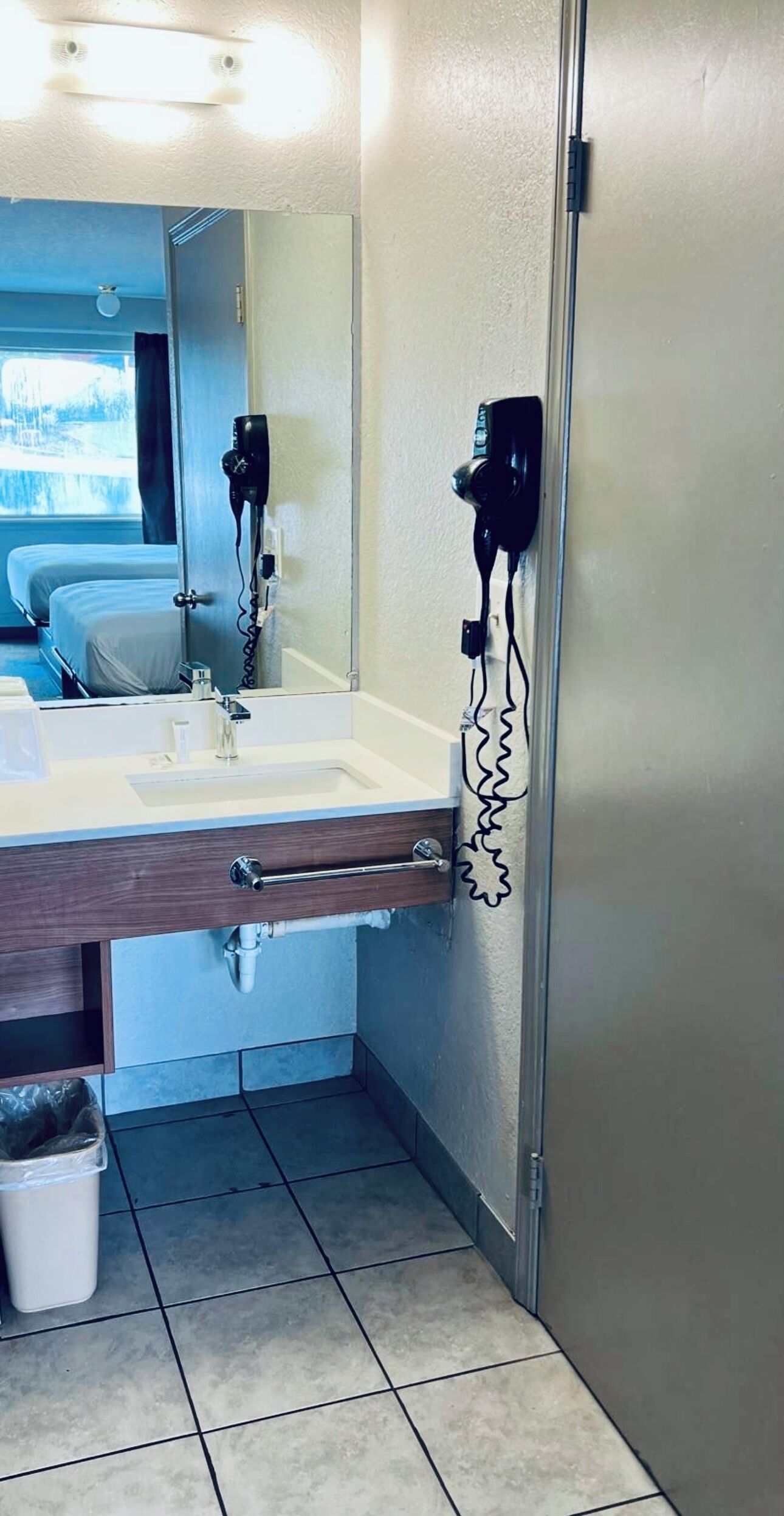Un baño con lavamanos, espejo, secador de pelo y toallero.