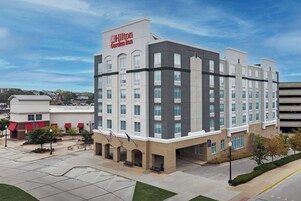 A modern Hilton Garden Inn with a central courtyard, multiple floors, and a parking garage in the background.