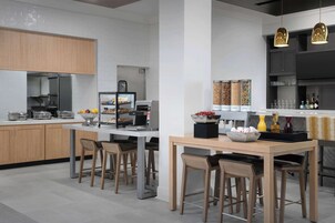 A modern kitchen with wooden cabinets, a central island with stools, and pendant lighting.
