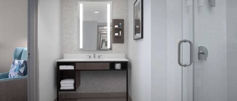 Une salle de bain moderne avec une porte de douche en verre, un lavabo blanc avec un miroir au-dessus et un porte-serviettes.