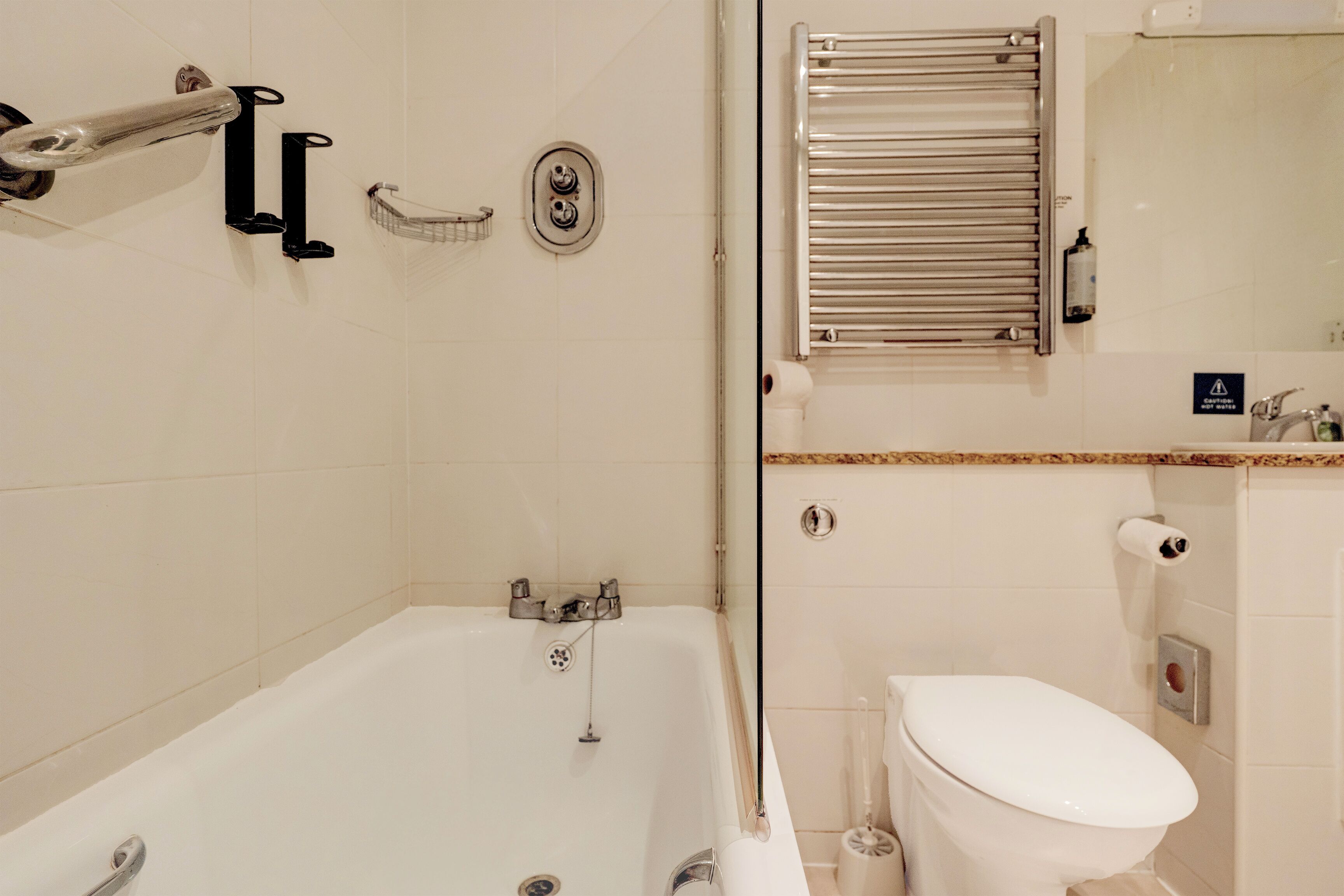 Un baño moderno con bañera, inodoro y un perchero para toallas.