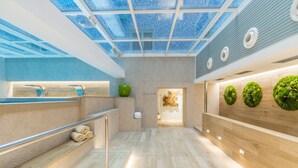 Un interior moderno con tragaluces, suelo de madera y una zona de recepción con una escultura de manzana verde.