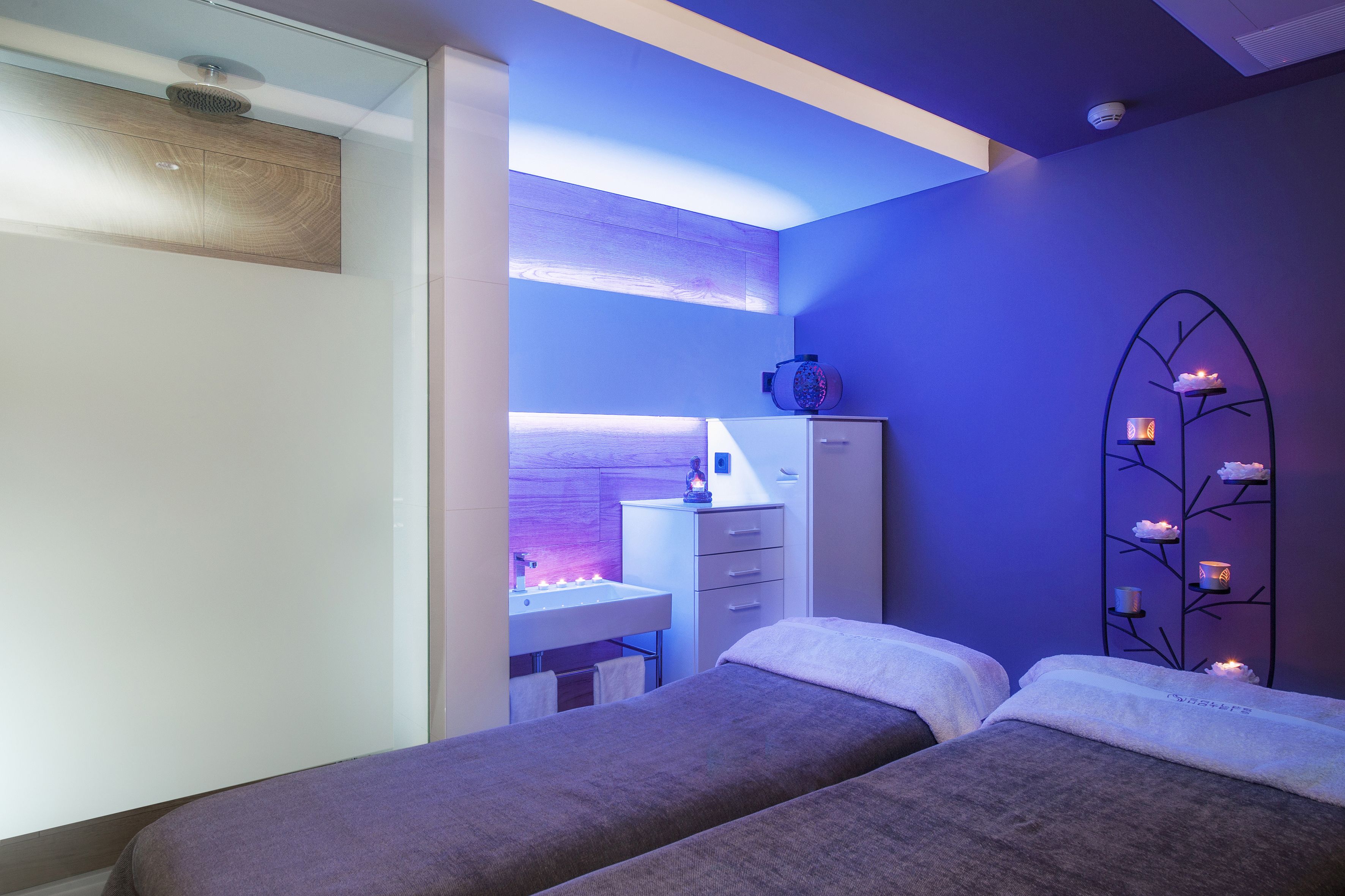 Una habitación moderna con dos camas, un tocador con espejo y un escritorio con computadora.