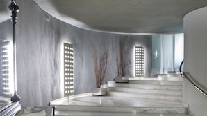 Un interior moderno con escaleras de mármol, decoración minimalista y un techo curvo.