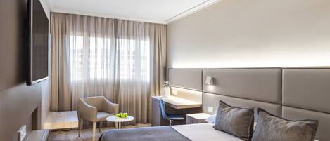 Une chambre d’hôtel moderne équipée d’un grand lit, d’un bureau, d’une chaise et d’un téléviseur.