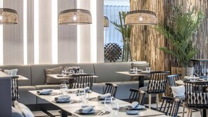 Un comedor moderno con una mesa larga dispuesta para una comida, rodeado de sofás y sillas.