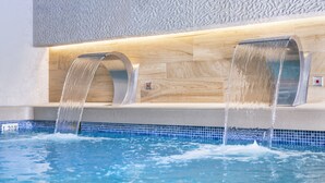 Una piscina interior moderna con dos juegos de agua.