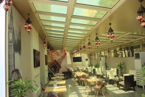 A cafe with a high ceiling, skylights, and hanging lanterns. - Holiday Inn Al Khobar by IHG (Al Khobar)