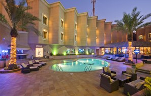A hotel courtyard with a swimming pool, lounge chairs, and palm trees. - Holiday Inn Al Khobar by IHG (Al Khobar)
