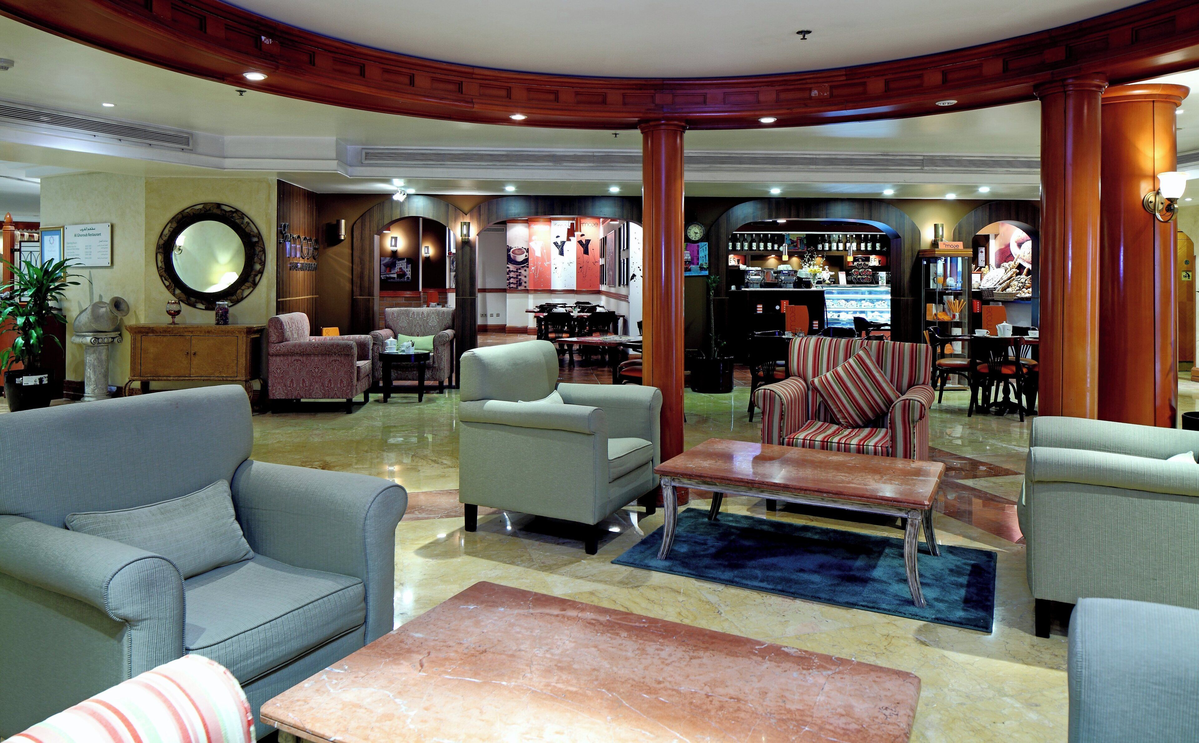 A hotel lobby with seating arrangements, a bar area, and a reception desk.