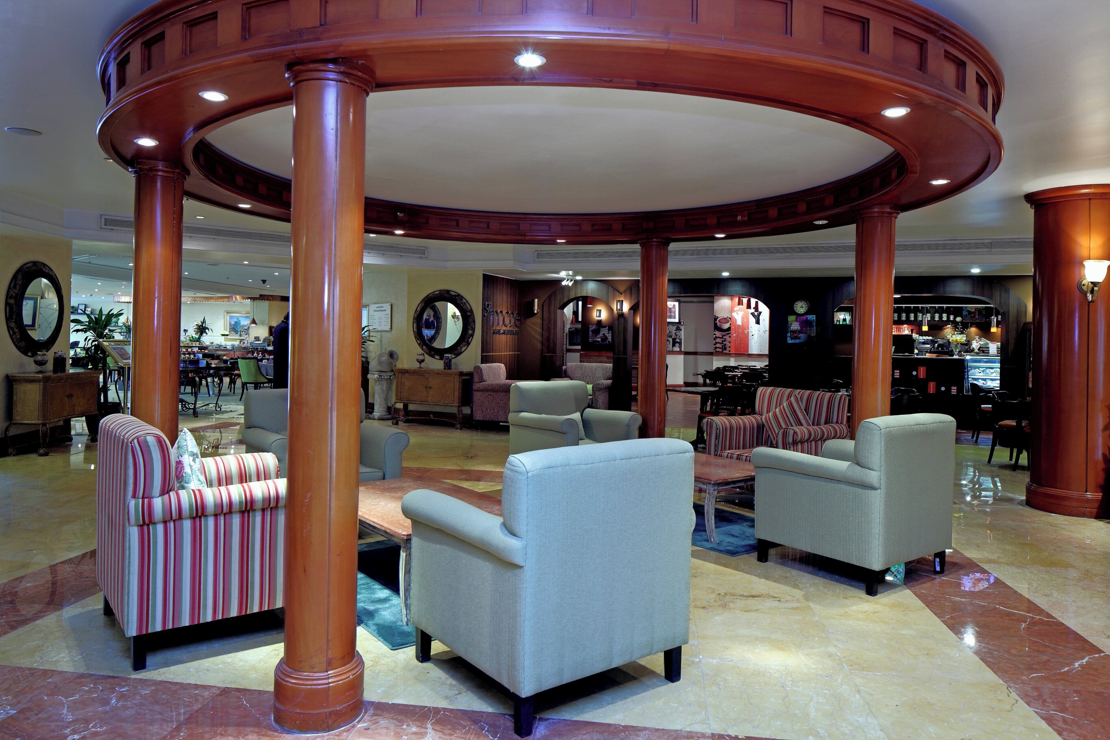 A lobby with a central column, seating area, and a bar in the background.