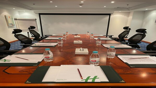 A conference room with a long table, chairs, water bottles, tissues, and documents. - Holiday Inn Al Khobar by IHG (Al Khobar)