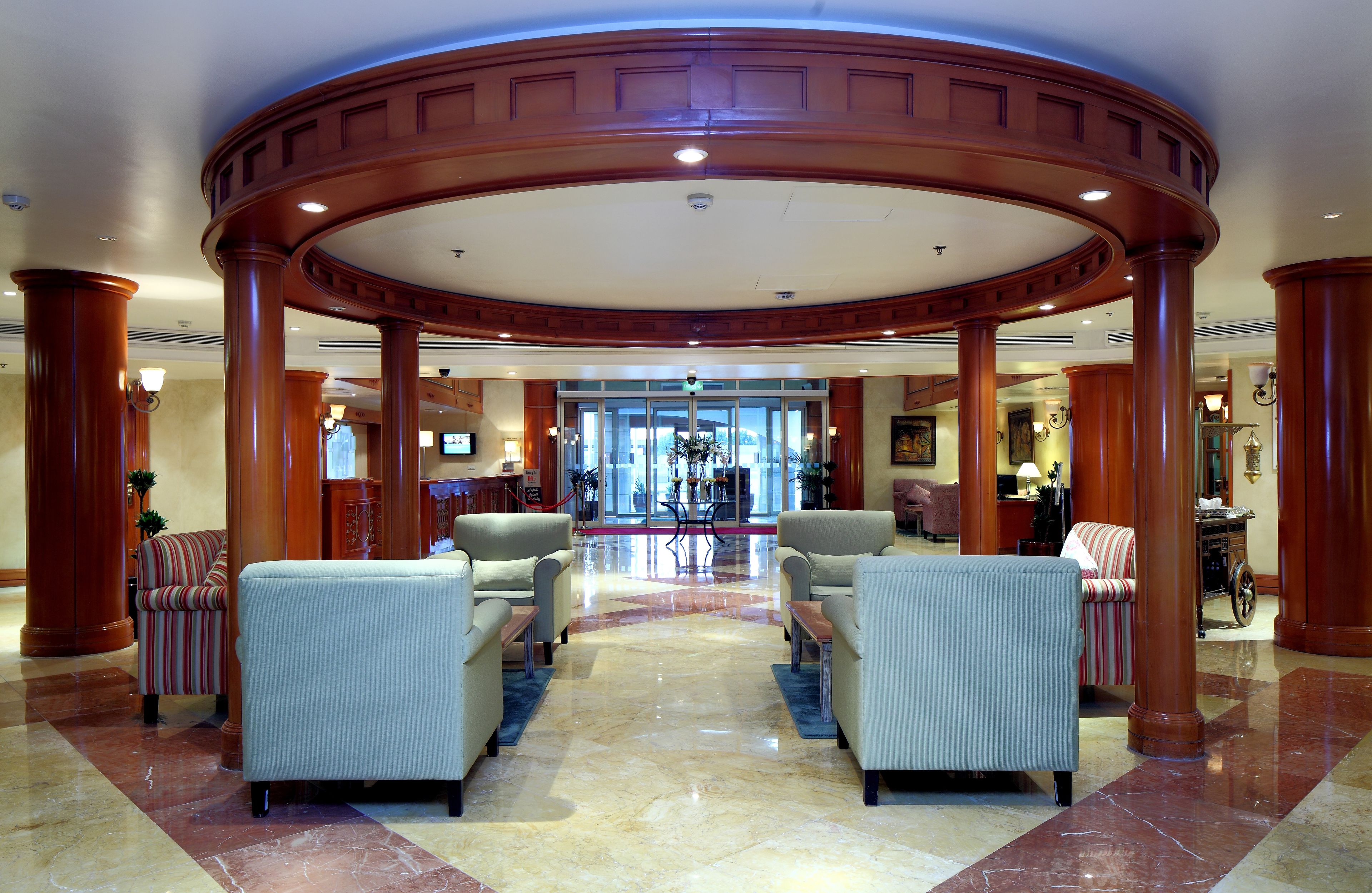 A lobby with a central seating area, a reception desk, and a view of the entrance.