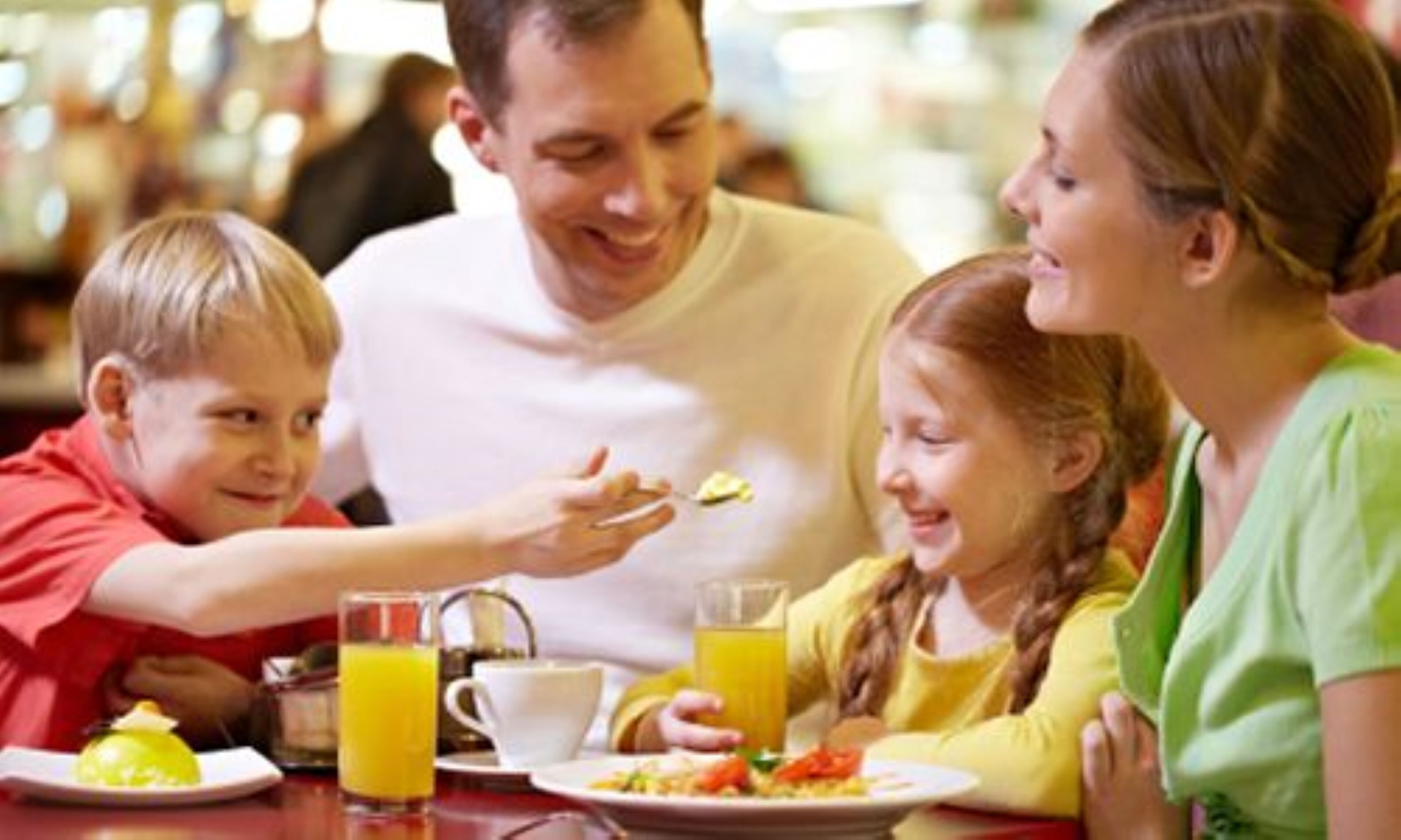A family dining at a restaurant with a table set for breakfast.