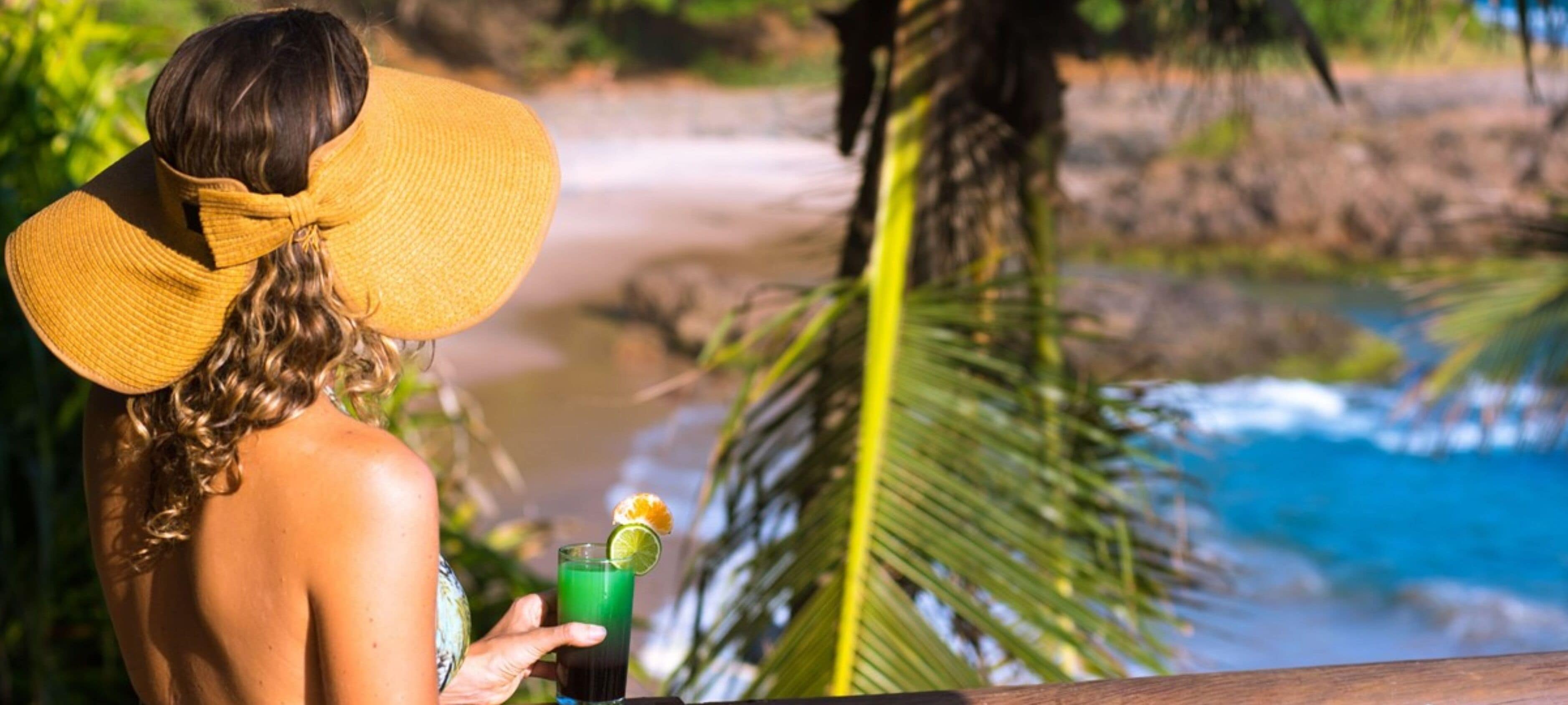 Une personne portant un grand chapeau jaune, qui surplombe une plage avec une piscine.