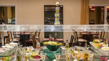 Disposição de buffet com diversos alimentos e uma estátua decorativa.