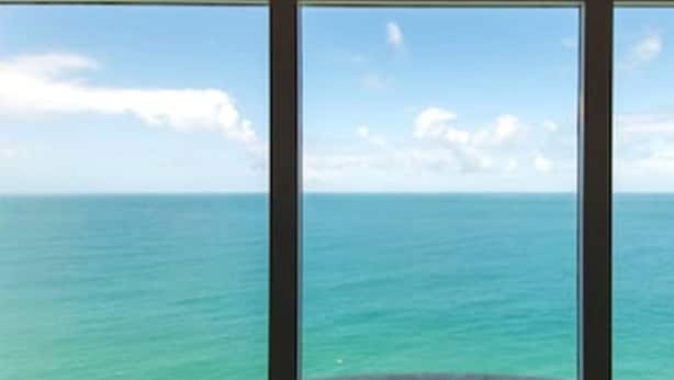 Visão através de uma janela, céu claro e mar calmo.