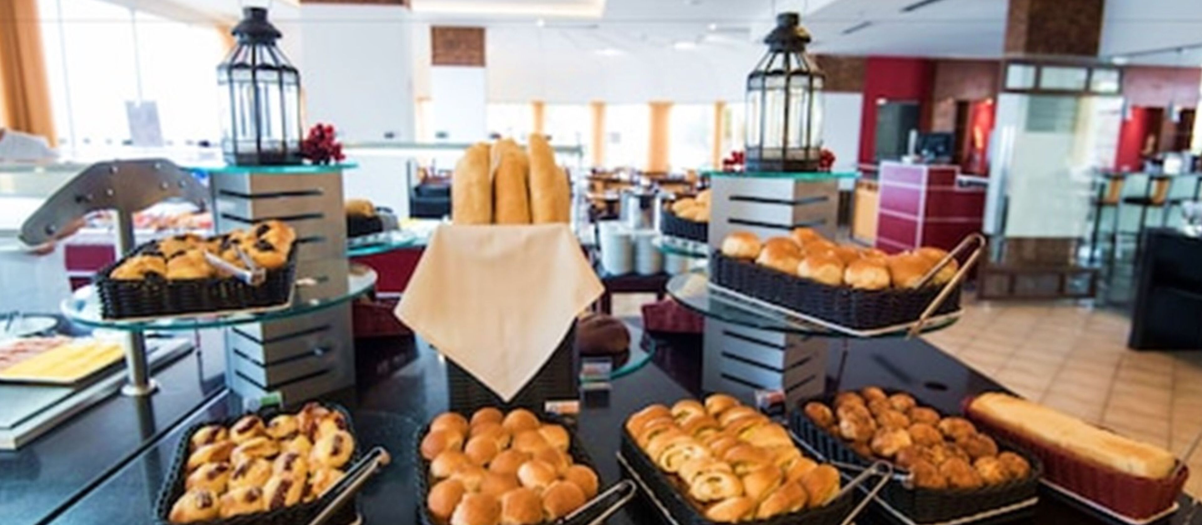 Zona de buffet con diversas opciones de panadería exhibidas en bandejas y soportes.