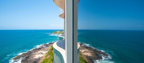 A coastal landscape with a curved pathway leading to a rocky island surrounded by turquoise waters. - Vila Gale Salvador (Salvador)
