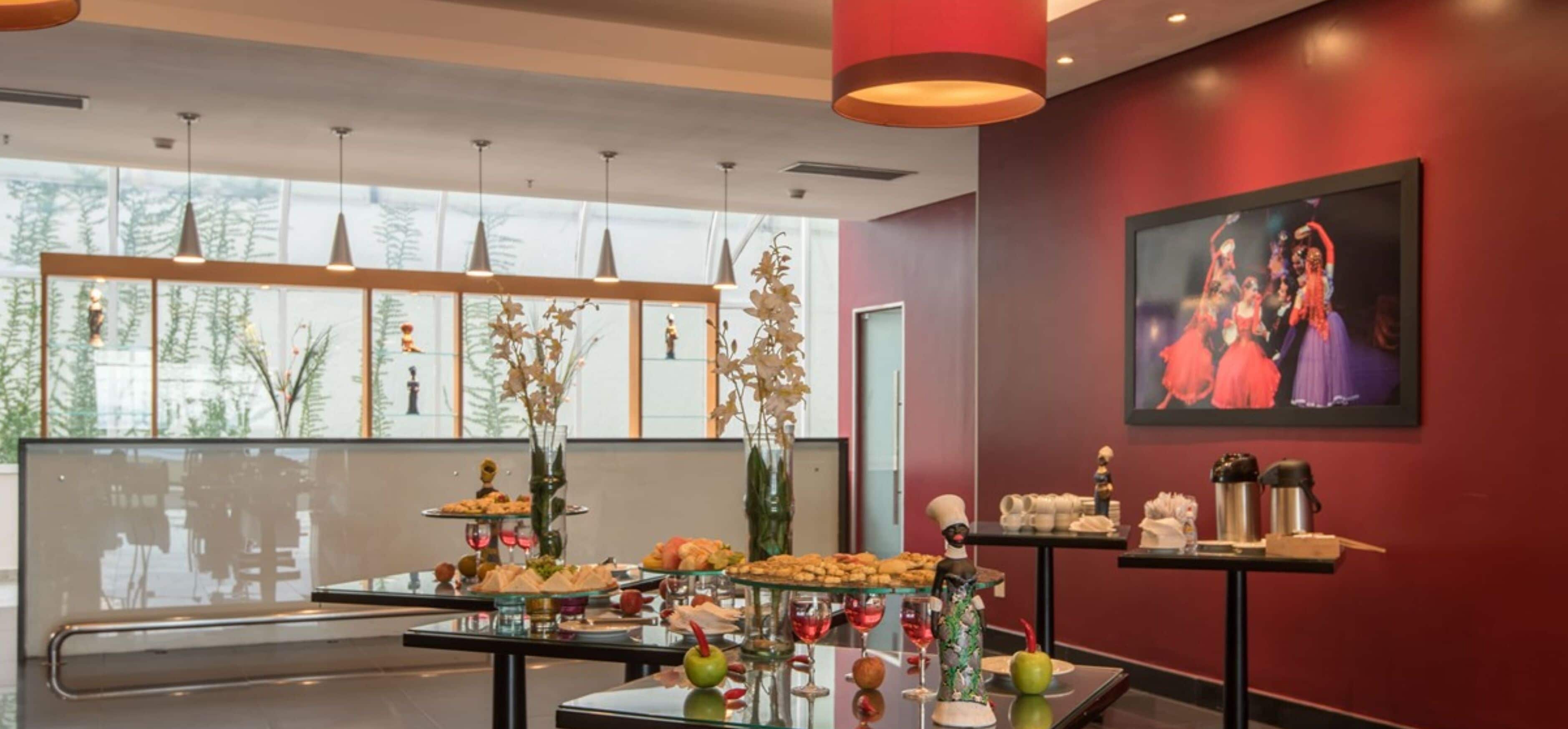 Un hall d’hôtel moderne avec une cloison en verre, des plantes décoratives et une œuvre d’art encadrée au mur.