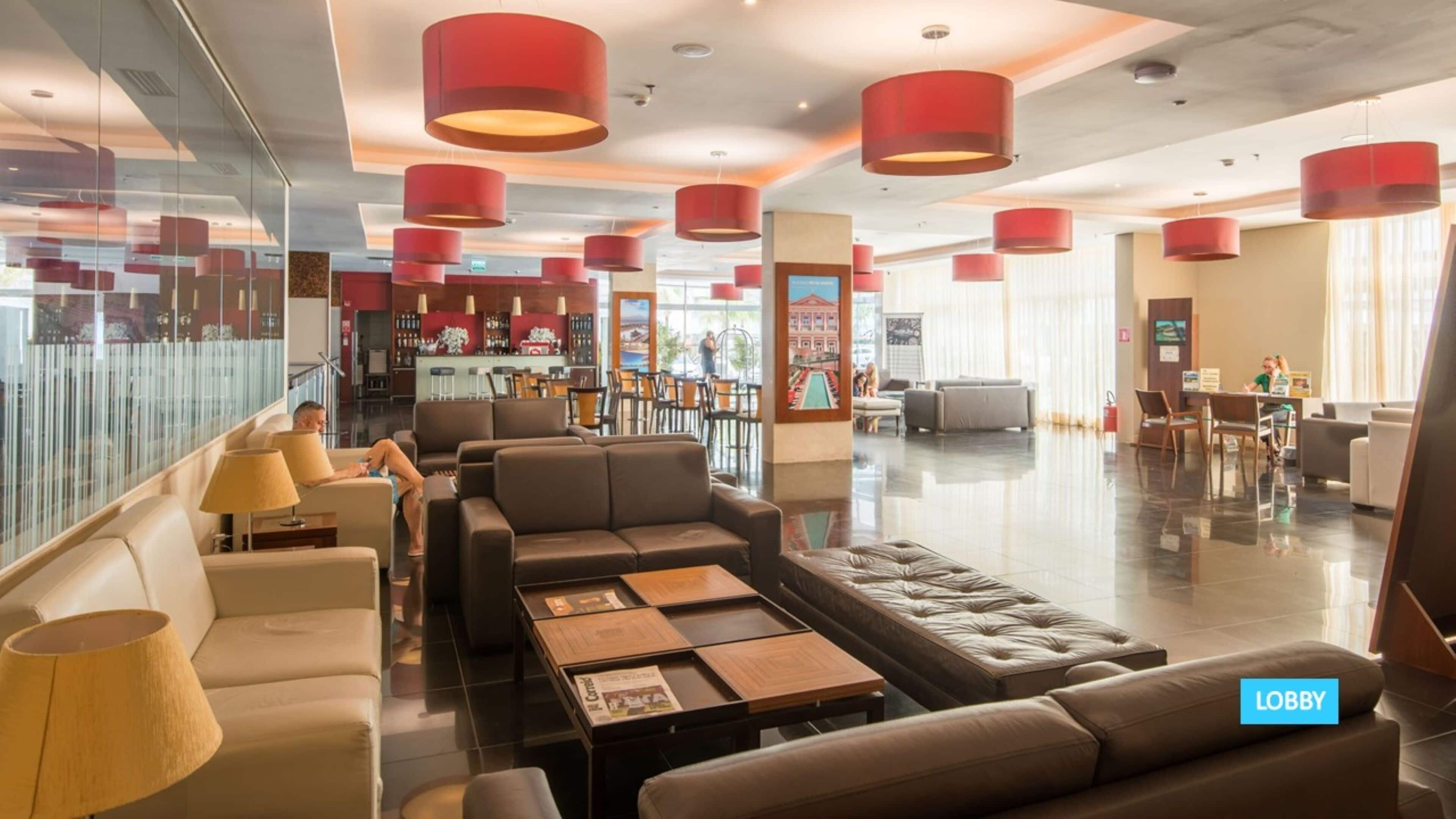 A lobby with leather sofas, a coffee table, and red pendant lights.