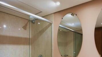 A modern bathroom with a glass shower enclosure, a large mirror, and a curved wall design.