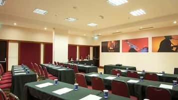 Uma sala de conferência com mesas e cadeiras dispostas em fileiras, equipada com placas de identificação e garrafas de água.